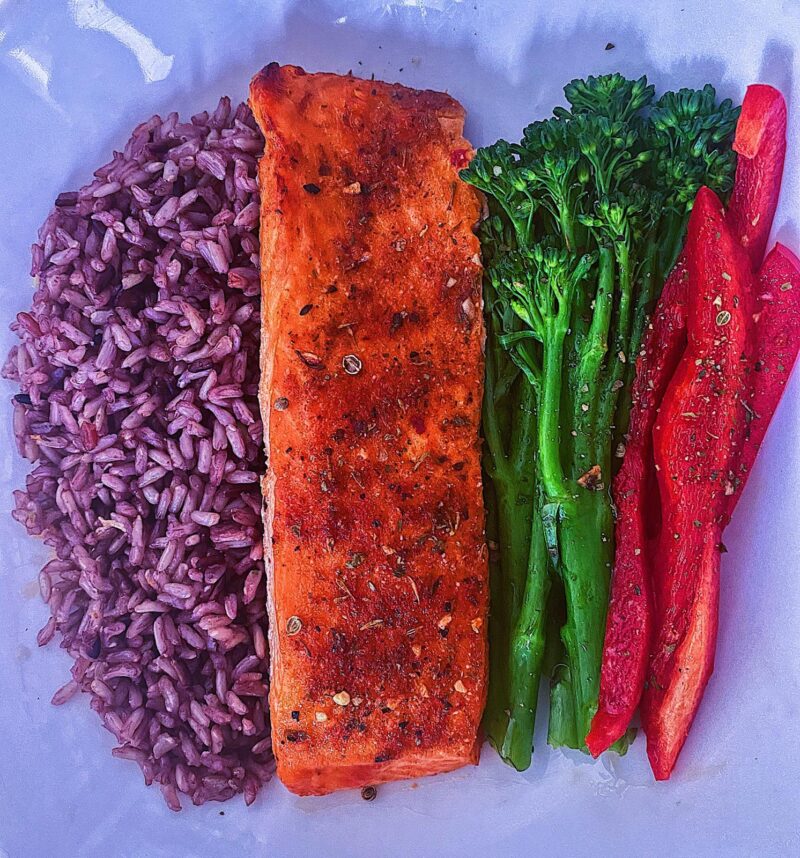 Cajun Baked Salmon, served with a side of multigrain rice, sweet broccolini and sweet red bell peppers