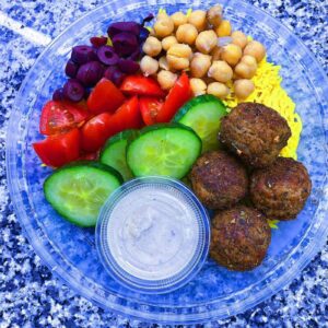 Falafel Bowl. Served with turmeric rice, black olives, cucumbers, tomatoes, chick peas, and a side of tahini sauce