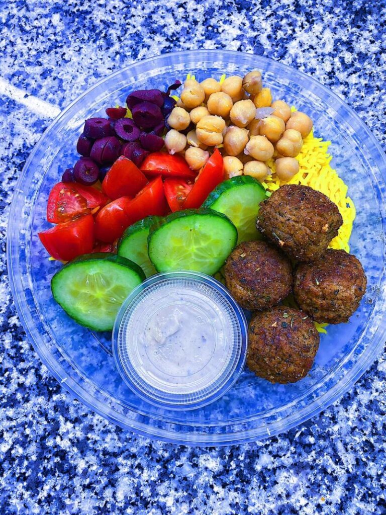 Falafel Bowl. Served with turmeric rice, black olives, cucumbers, tomatoes, chick peas, and a side of tahini sauce
