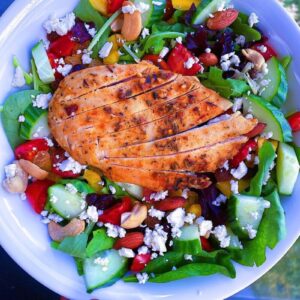 California Power Salad. Made with spring mix, tomatoes, cucumbers, red bell peppers, raisins, dried cranberries, sunflower seeds and feta cheese. Served with a side of honey citrus dressing