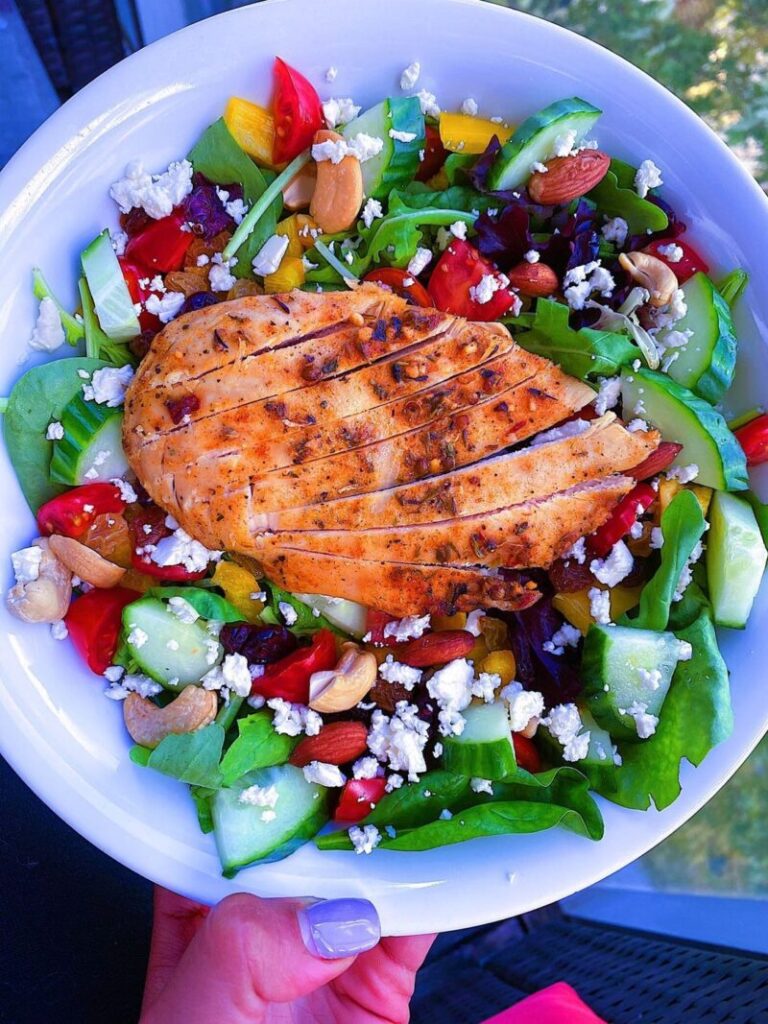 California Power Salad. Made with spring mix, tomatoes, cucumbers, red bell peppers, raisins, dried cranberries, sunflower seeds and feta cheese. Served with a side of honey citrus dressing
